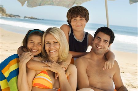 simsearch:693-03309308,k - Family in swimwear sitting together on beach, portrait Stock Photo - Premium Royalty-Free, Code: 693-06014709