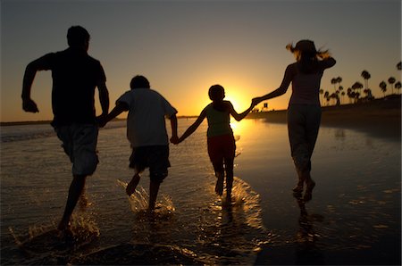 parent holding hands child silhouette - Family running through sea holding hands at sunset, back view, silhouette Stock Photo - Premium Royalty-Free, Code: 693-06014716