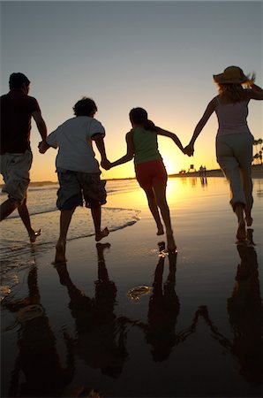 family holding hands on beach at sundown - Family running through sea at sunset, back view, silhouette Stock Photo - Premium Royalty-Free, Code: 693-06014718