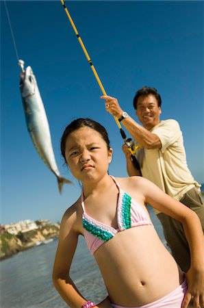 pictures of dad and daughter fishing - Man showing fish to daughter (7-9) at ocean Stock Photo - Premium Royalty-Free, Code: 693-06014724