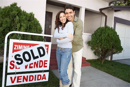 Couple standing in front of house with Sold sign, portrait Stock Photo - Premium Royalty-Free, Code: 693-06015046