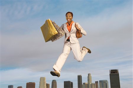 Woman jumping with shopping bags mid-air above city Stock Photo - Premium Royalty-Free, Code: 693-06015185