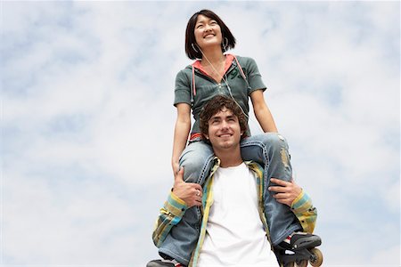 Young woman on shoulders of man, low angle view Stock Photo - Premium Royalty-Free, Code: 693-06015497