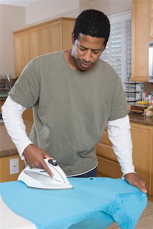 Mid-adult man ironing shirt in domestic kitchen Stock Photo - Premium Royalty-Free, Code: 693-06016193