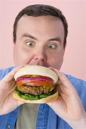 fat man facial expression - Overweight mid-adult man eating hamburger Stock Photo - Premium Royalty-Free, Code: 693-06016339