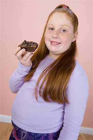 fat kid eating junk food - Overweight girl holding brownie, portrait Stock Photo - Premium Royalty-Free, Code: 693-06016347