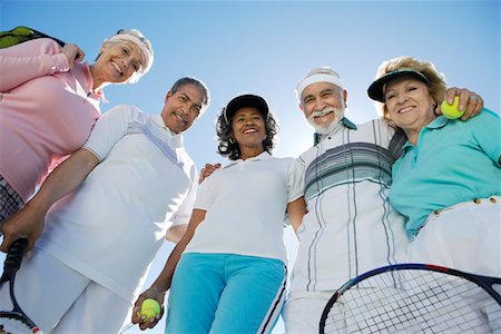friends tennis - Seniors standing in half circle, holding rackets and balls, low angle view Stock Photo - Premium Royalty-Free, Code: 693-06016593