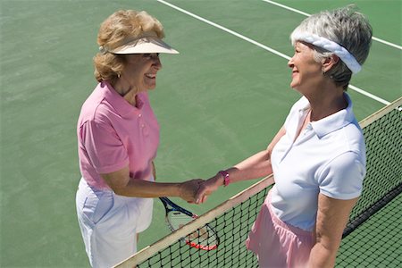 Two women shaking hands over tennis net Stock Photo - Premium Royalty-Free, Code: 693-06016639