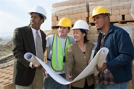 Two architects and two construction workers standing on construction site holding blueprints Stock Photo - Premium Royalty-Free, Code: 693-06016827