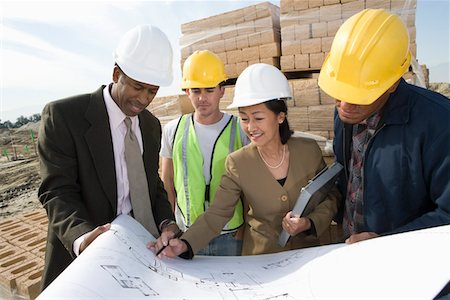 Two architects and two construction workers standing on construction site holding blueprints Stock Photo - Premium Royalty-Free, Code: 693-06016829