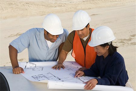 Architect and two construction workers looking at blueprints on construction site Stock Photo - Premium Royalty-Free, Code: 693-06016857