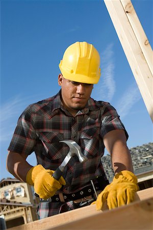 Construction worker hammering nail on construction site Stock Photo - Premium Royalty-Free, Code: 693-06016886