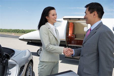 Business People standing near sports car and private airplane, Shaking Hands, side view Stock Photo - Premium Royalty-Free, Code: 693-06016937