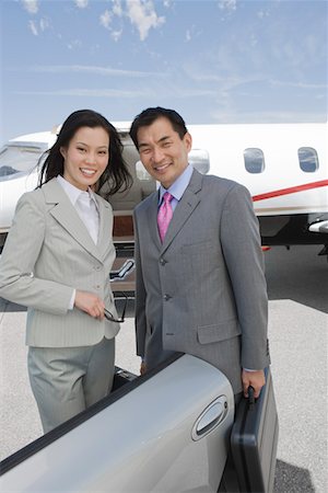 Portrait of mid-adult businesswoman and mid-adult businessman standing in front of private plane. Stock Photo - Premium Royalty-Free, Code: 693-06016955
