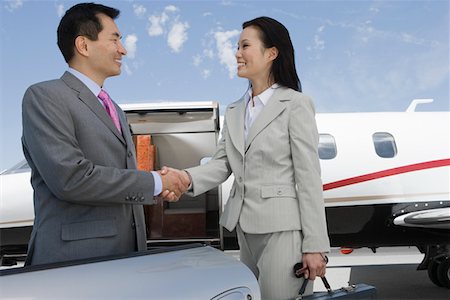 Mid-adult businesswoman and mid-adult businessman shaking hands in front of private plane. Stock Photo - Premium Royalty-Free, Code: 693-06016956