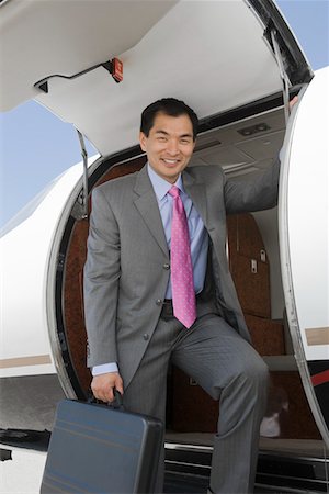 Portrait of Asian businessman getting off private airplane. Stock Photo - Premium Royalty-Free, Code: 693-06016965