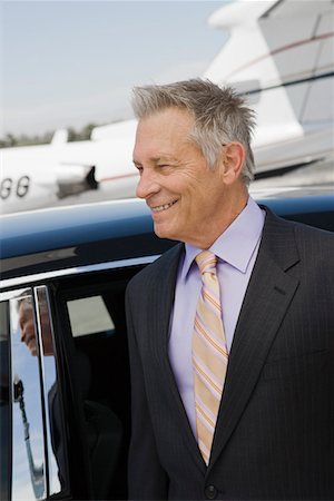 Senior businessman in front of limousine and private jet. Stock Photo - Premium Royalty-Free, Code: 693-06017016