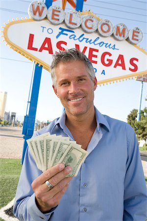 simsearch:693-06018149,k - Mid-adult man holding notes in front of Welcome to Las Vegas sign, portrait Stock Photo - Premium Royalty-Free, Code: 693-06018065