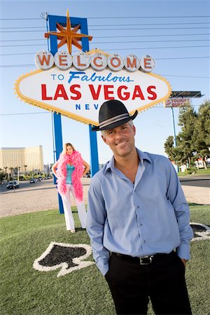 simsearch:693-06018149,k - Portrait of mid-adult man in front of Welcome to Las Vegas sign, mid-adult woman behind. Stock Photo - Premium Royalty-Free, Code: 693-06018067