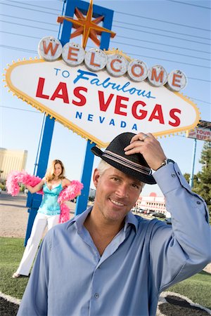 simsearch:693-06018149,k - Portrait of mid-adult man in front of Welcome to Las Vegas sign, mid-adult woman in background. Stock Photo - Premium Royalty-Free, Code: 693-06018068
