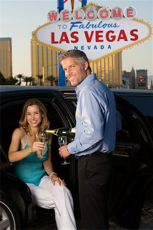 Mid-adult couple sitting in limousine and drinking champagne in front of Welcome to Las Vegas sign Stock Photo - Premium Royalty-Free, Code: 693-06018081