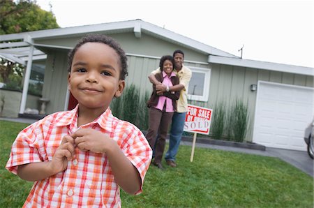 Portrait of boy (5-6) in front of new house, parents in background Stock Photo - Premium Royalty-Free, Code: 693-06018217