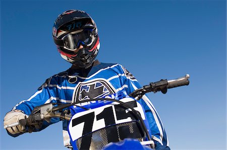 Motocross racer on bike against blue sky, (low angle view) Stock Photo - Premium Royalty-Free, Code: 693-06018236