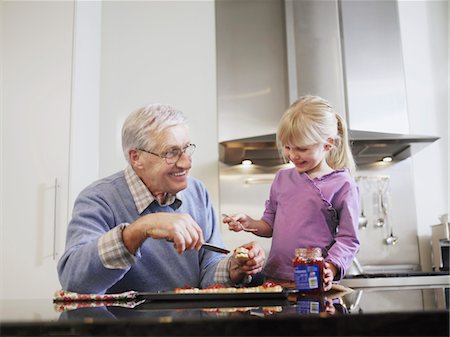 Girl (3-4) and grandfather spreading jam on biscuits in kitchen Stock Photo - Premium Royalty-Free, Code: 693-06018500