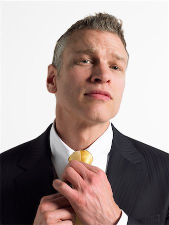 Man adjusting tie in studio, head and shoulders Stock Photo - Premium Royalty-Free, Code: 693-06018623