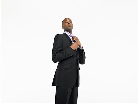 Businessman adjusting tie in studio Stock Photo - Premium Royalty-Free, Code: 693-06018630