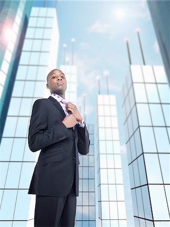 Businessman adjusting tie in front of skyscraper, digital composite Foto de stock - Sin royalties Premium, Código: 693-06018650