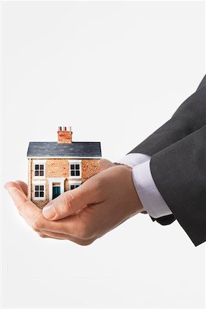 selling house - Business man holding model house in cupped hands, view of hands Stock Photo - Premium Royalty-Free, Code: 693-06018738