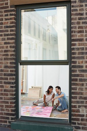 Couple sitting by painting on floor of artist studio, view through window Stock Photo - Premium Royalty-Free, Code: 693-06018848
