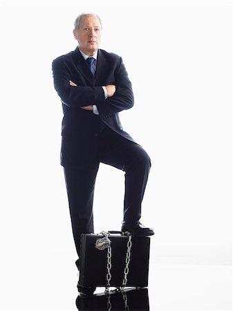 Businessman with foot on chained briefcase Stock Photo - Premium Royalty-Free, Code: 693-06018987