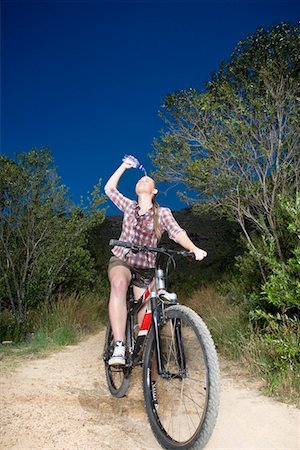 Teenage girl (16-17 years) on bike on dirt road, spilling water over face Foto de stock - Sin royalties Premium, Código: 693-06019097