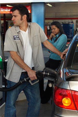 Woman watching gas station attendant pumping gas Stock Photo - Premium Royalty-Free, Code: 693-06019263