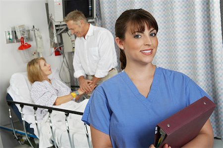 examination folder - Portrait of female nurse in hospital room, patient in background Stock Photo - Premium Royalty-Free, Code: 693-06019281