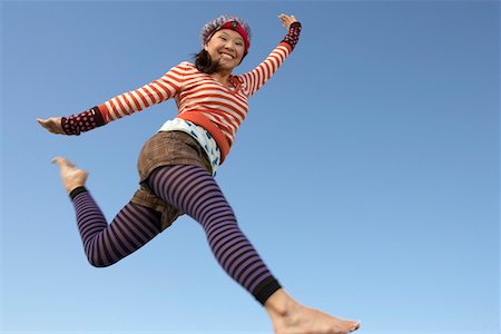 Young woman jumping in striped outfit Stock Photo - Premium Royalty-Free, Code: 693-06019419