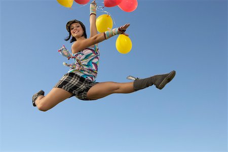 Young woman doing splits in air holding balloons Stock Photo - Premium Royalty-Free, Code: 693-06019420