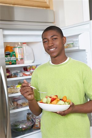 Young man eating salad by open fridge Stock Photo - Premium Royalty-Free, Code: 693-06019483