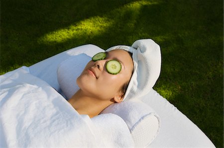 Young woman with cucumbers over eyes, lying on massage table outdoors Stock Photo - Premium Royalty-Free, Code: 693-06019680