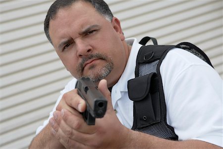 security guard one person - Portrait of security guard in bulletproof vest holding gun Stock Photo - Premium Royalty-Free, Code: 693-06019799