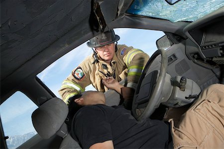 Firefighter looking into crashed car, view from interior Stock Photo - Premium Royalty-Free, Code: 693-06019854