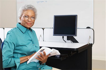 Female teacher holding book in computer classroom, portrait Stock Photo - Premium Royalty-Free, Code: 693-06019885