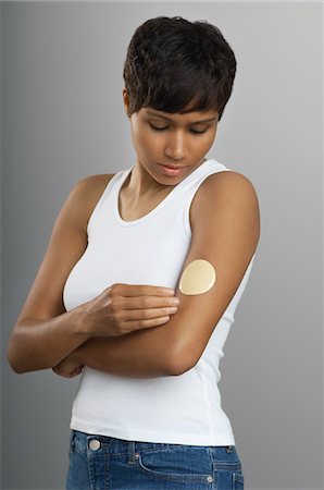 sick black woman - Woman with patch on arm, studio shot Stock Photo - Premium Royalty-Free, Code: 693-06019979