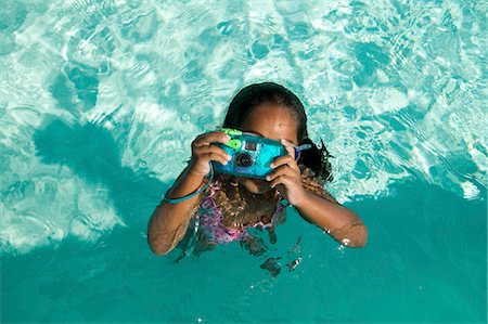 Girl (5-6) Using Waterproof Camera in Swimming Pool, overhead view. Stock Photo - Premium Royalty-Free, Code: 693-06013558