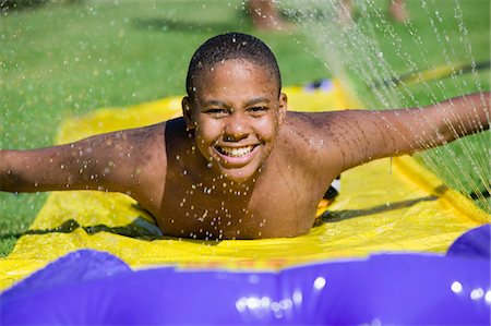 stop-action - Boy (10-12) Sliding on water slide, front view portrait. Fotografie stock - Premium Royalty-Free, Codice: 693-06013563