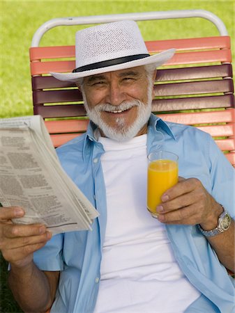 simsearch:693-06019332,k - Senior Man sitting on Lawn Chair holding Newspaper and Orange Juice, elevated view portrait. Stock Photo - Premium Royalty-Free, Code: 693-06013604