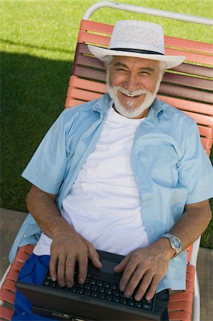 Senior Man sitting on Lawn Chair Using Laptop, elevated view portrait. Stock Photo - Premium Royalty-Free, Code: 693-06013605