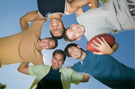 simsearch:693-06013621,k - Boy (13-15) holding football, with brothers and father in huddle, view from below. Stock Photo - Premium Royalty-Free, Code: 693-06013620